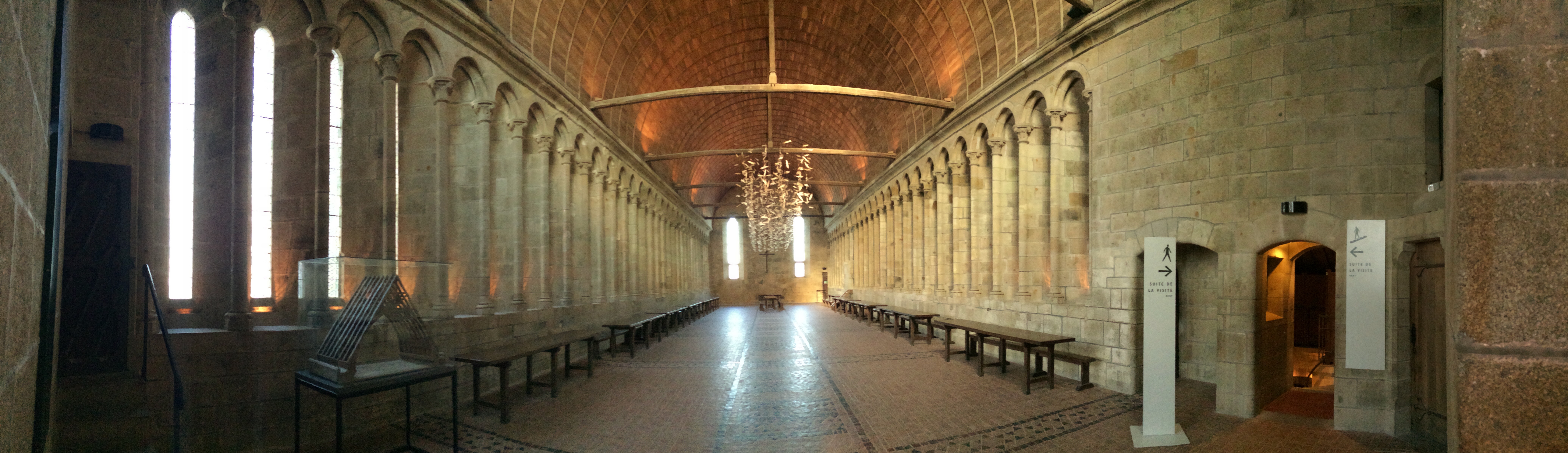 Długi refektarz opactwa Mont-Saint-Michel z kamiennymi arkadami i drewnianym sklepieniem