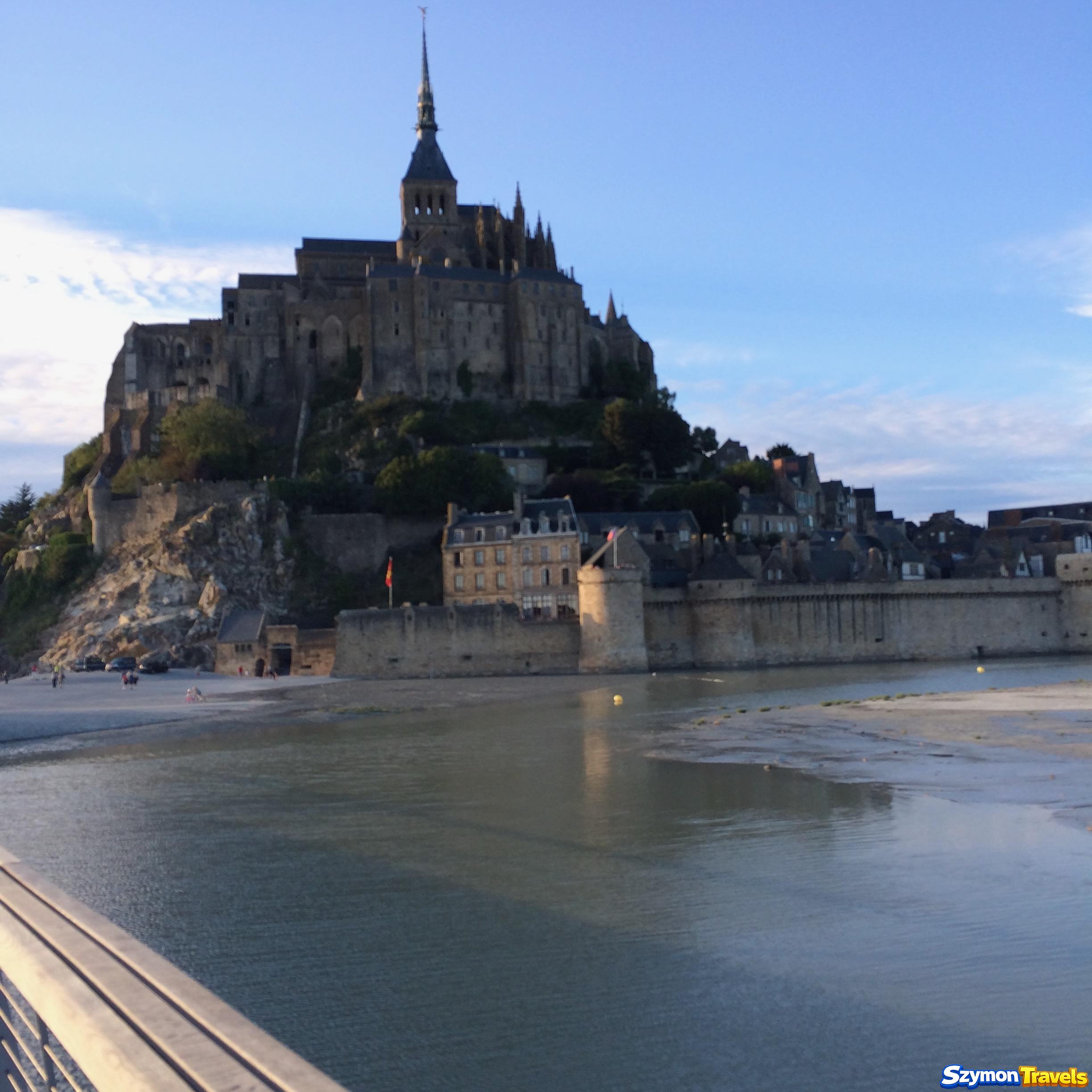 Mont-Saint-Michel oglądany późnym popołudniem z wodą i piaskiem przy murach