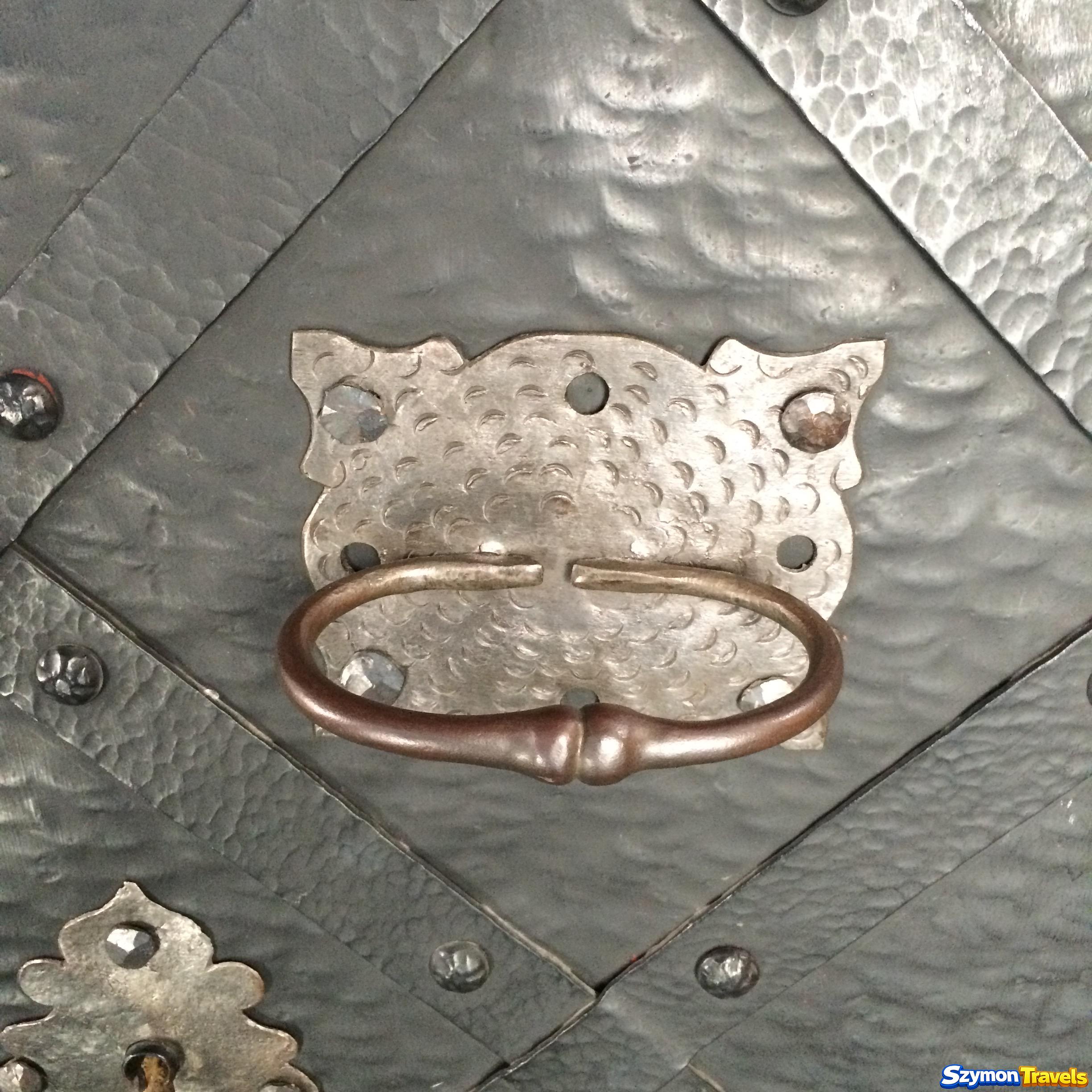 Metalowa antaba na ozdobnych kutych drzwiach sfotografowana podczas zwiedzania Lublina