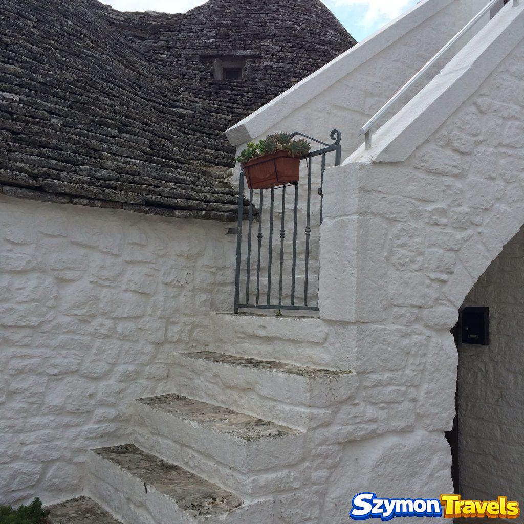 Białe zewnętrzne schody pomiędzy kamiennymi dachami trulli w Alberobello