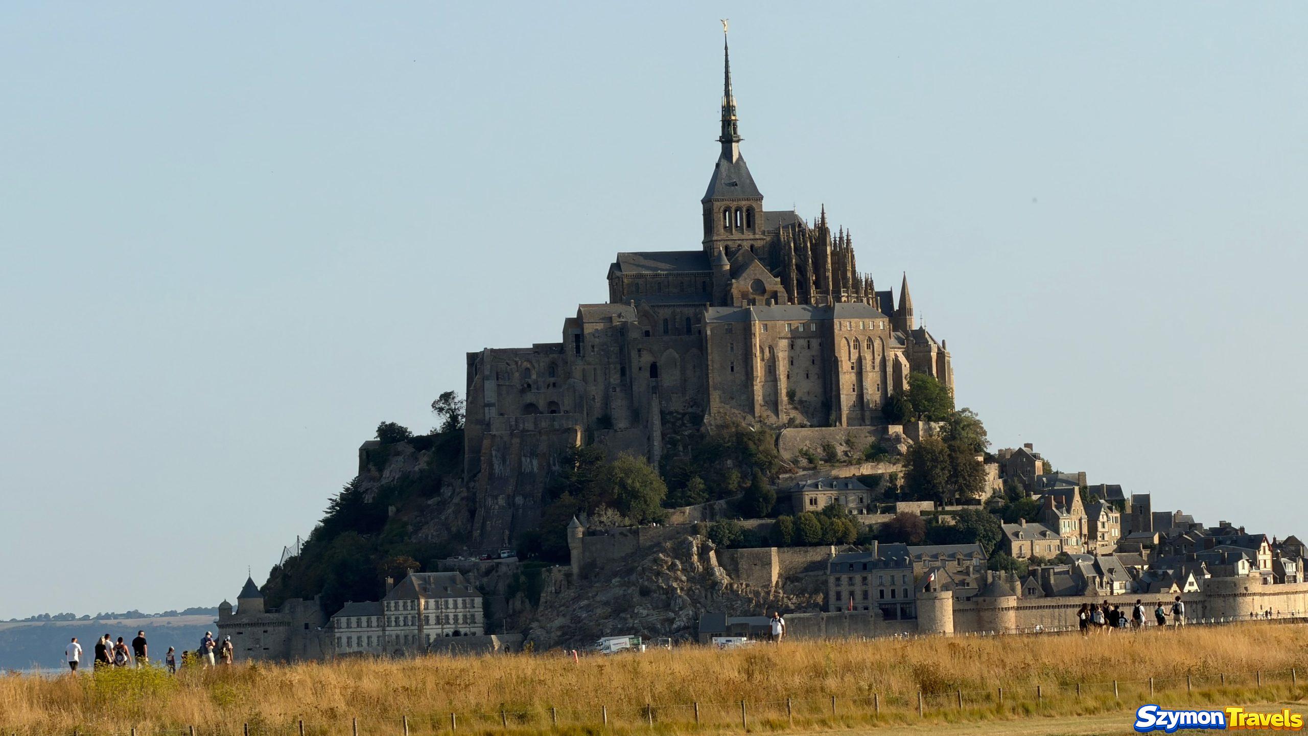 Mont-Saint-Michel ponad łąkami Mont-Saint-Michel ponad łąkami z turystami na pieszej trasie
