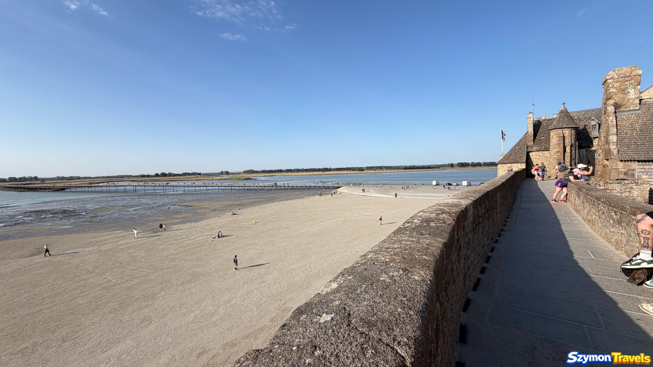 Mury Mont-Saint-Michel Spacer po murach Mont-Saint-Michel z widokiem na zatokę podczas odpływu